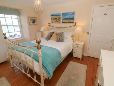 a bedroom with a bed with a white bed frame at April Cottage in Falmouth