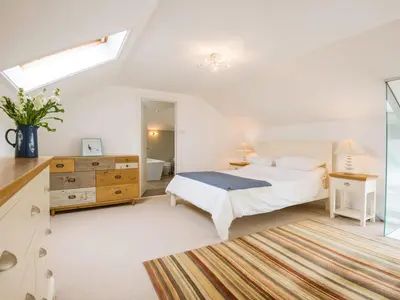 a white bedroom with a bed and a window at Moorlands Bungalow in Wadebridge