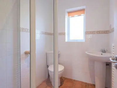 a white bathroom with a toilet and a sink at Moorlands Bungalow in Wadebridge