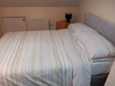 a bedroom with a bed with a striped comforter at The Old Barn in Tintagel