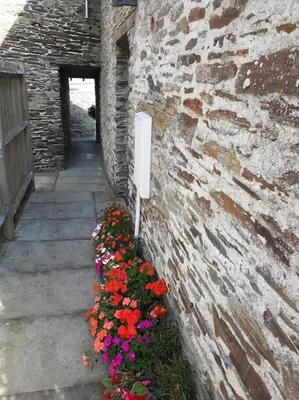 a brick wall with a bunch of flowers next to a building at The Old Barn in Tintagel
