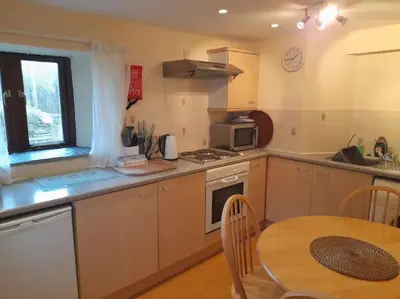 a kitchen with a wooden table and a table and a dining room at The Old Barn in Tintagel