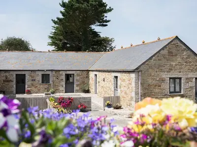 a stone building with flowers in front of it at Eglos Derry Farm Cottage - E4597 in Cury