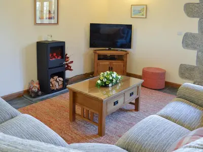a living room with a coffee table and a tv at Eglos Derry Farm Cottage - E4597 in Cury
