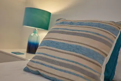 a striped pillow sitting on a bed with a lamp at Stunning Apartment Balcony Sea Views St Ives in St Ives