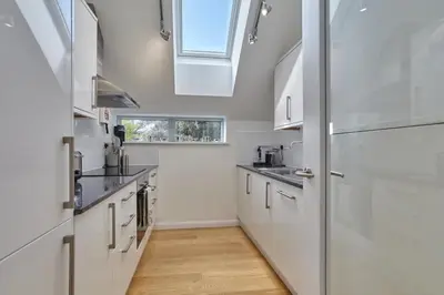 a kitchen with white cabinets and a skylight at Stunning Apartment Balcony Sea Views St Ives in St Ives