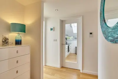 a room with a dresser and a mirror and a hallway at Stunning Apartment Balcony Sea Views St Ives in St Ives