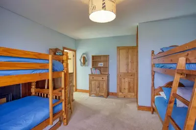 a bedroom with three bunk beds and a hallway at Historic Chapel Great Facilities nr Beaches in Saint Ewe