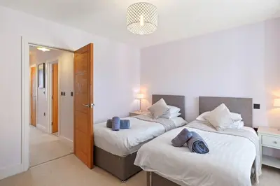 a bedroom with two beds and a hallway with a door at Townhouse Parking 1 Min Walk to Tolcarne Beach in Newquay