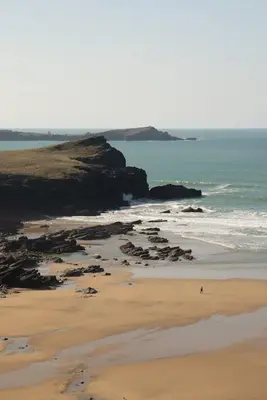 a person walking on a beach near the ocean at Townhouse Parking 1 Min Walk to Tolcarne Beach in Newquay