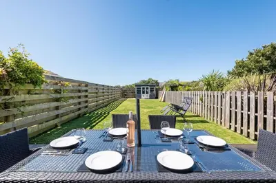 a blue table with plates and glasses on a fence at Modern House in St Agnes Parking & Garden in St. Agnes