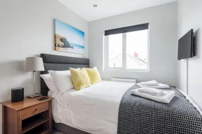 a white bedroom with a bed and a window at Modern House in St Agnes Parking & Garden in St. Agnes