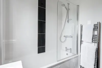 a bathroom with a shower and a sink with a mirror at Modern House in St Agnes Parking & Garden in St. Agnes