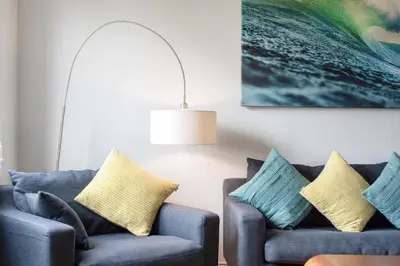 a living room with two blue couches and a painting at Modern House in St Agnes Parking & Garden in St. Agnes