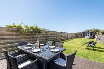 a table and chairs on a deck with a yard at Modern House in St Agnes Parking & Garden in St. Agnes
