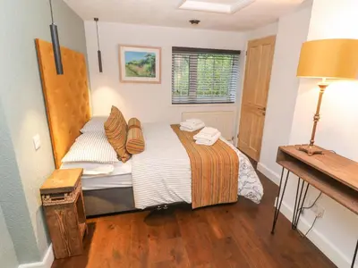 a bedroom with a bed and a table and a lamp at Dowager Cottage in Penryn