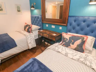 a room with two beds and a mirror at Dowager Cottage in Penryn