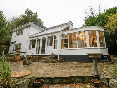 a white house with windows and a patio at Dowager Cottage in Penryn