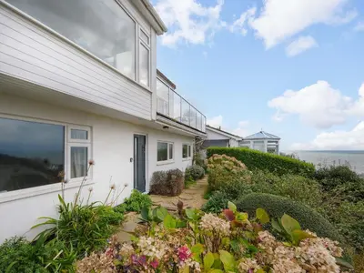 a white house with a garden in front of it at Waves Edge in Torpoint