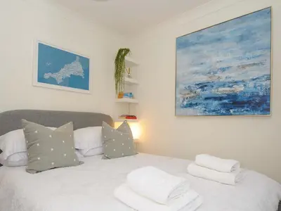 a bedroom with a bed with pillows and a painting at Waves Edge in Torpoint