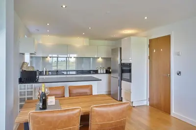 a kitchen and dining room with a wooden table and chairs at Apartment Sea Views 5 mins Walk to Fistral in Newquay