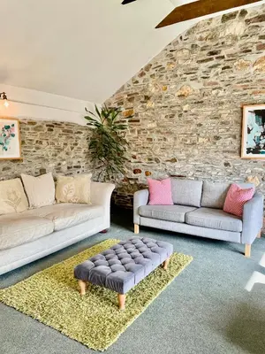 a living room with two couches and a stone wall at The Hay Loft in Bude