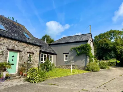 an old stone house with a green door at The Hay Loft in Bude