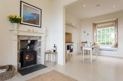 a living room with a fireplace and a table at Romantic cottage with fantastic coastal views in Marazion
