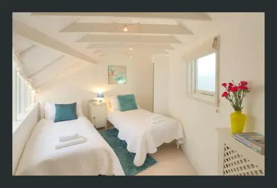 a small room with two beds and a table at No 11 Fish Street, St Ives in St Ives
