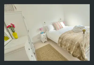 a white bedroom with a bed and a mirror at No 11 Fish Street, St Ives in St Ives