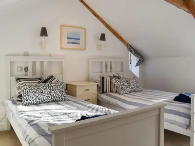 two beds in a room with white walls at Stones Throw in Padstow