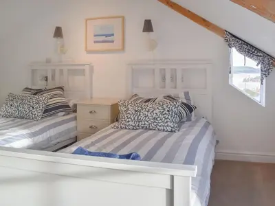 two beds in a room with white walls at Stones Throw in Padstow
