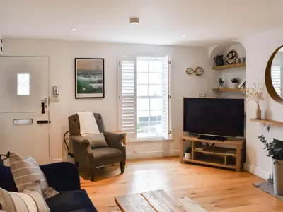 a living room with a television and a chair at Stones Throw in Padstow