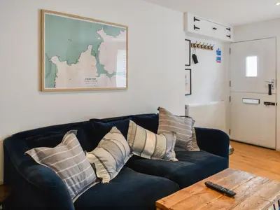 a living room with a blue couch and a table at Stones Throw in Padstow