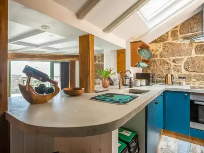 a kitchen with blue cabinets and a stone wall at Cottage Uk48457 in St Ives