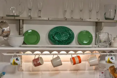 a shelf with green plates and cups on it at Finest Retreats - The Noel at Lesceave in Praa Sands