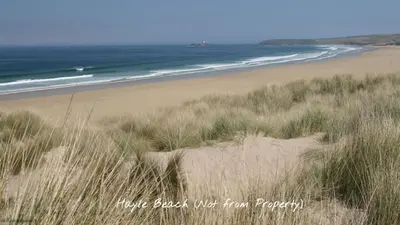 a sandy beach with grass and the ocean at 14 Tudor Court, Tolroy Manor in Hayle
