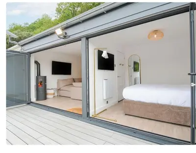 a room with a bed and a sliding glass door at Newly Refurbished Beach Lodge in Looe