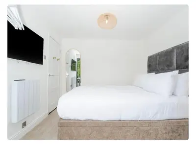 a bedroom with a white bed and a flat screen tv at Newly Refurbished Beach Lodge in Looe