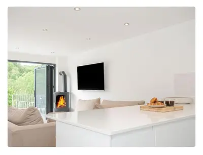a white living room with a fireplace and a couch at Newly Refurbished Beach Lodge in Looe