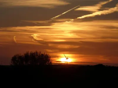 a sunset with a wind turbine on a hill at Silverspring Hideaways in Constantine