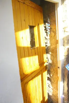 a wooden door in a room with a stone wall at The Old Barn near St Ives - Rustic Charm & Space in St Ives