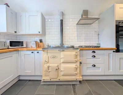 an old fashioned stove in a kitchen with white cabinets at The Old Barn near St Ives - Rustic Charm & Space in St Ives