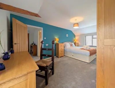 a bedroom with a bed and a blue wall at The Old Barn near St Ives - Rustic Charm & Space in St Ives