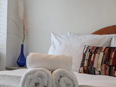 a bed with two towels and a blue vase at The Old Barn near St Ives - Rustic Charm & Space in St Ives