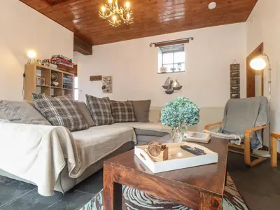 a living room with a couch and a table at Owl Cottage in Looe
