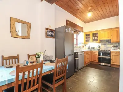 a kitchen with a table and a stainless steel refrigerator at Owl Cottage in Looe