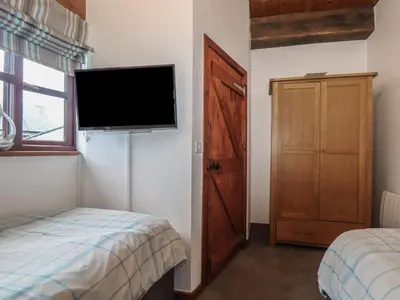 a bedroom with a flat screen tv and a bed at Owl Cottage in Looe