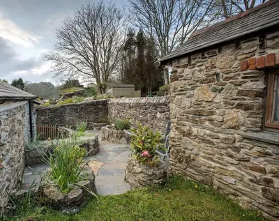 a stone building with a stone wall and some plants at Carole's Cottage - Private Parking, Sea Views, Garden & Close To Harbour & Beach in Charlestown