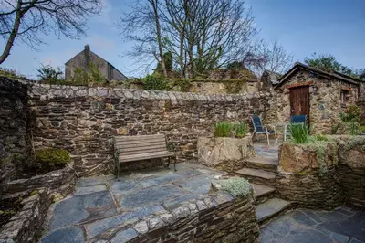 a stone wall with a bench and a building at Carole's Cottage - Private Parking, Sea Views, Garden & Close To Harbour & Beach in Charlestown